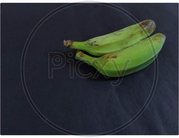 Raw banana on black background.