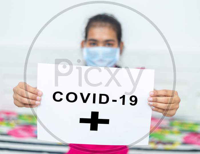 Young Girl Wearing Surgical Protection Mask Holding White Board With Text Covid-19 During Quarantine. Stay At Home Concept.