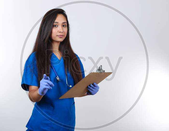 A Young Nurse Holding A Clip Board Points Her Finger.