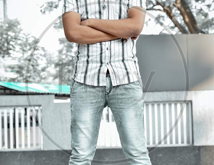 Man wearing white strip shirt and cool denims with sunglasses folded hands posing for photoshoot