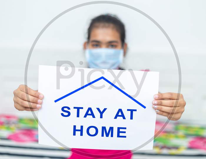 Young Girl Wearing Surgical Protection Mask Holding White Board With Text Stay At Home Concept During Quarantine