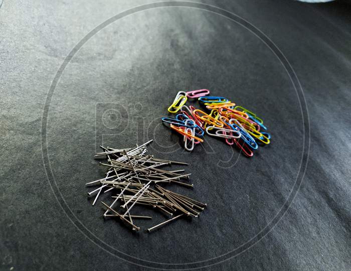 View of paperclip  and pin on black background.