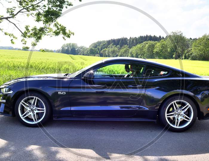 Black sports car in front of a northern germany landscapes on a sunny day