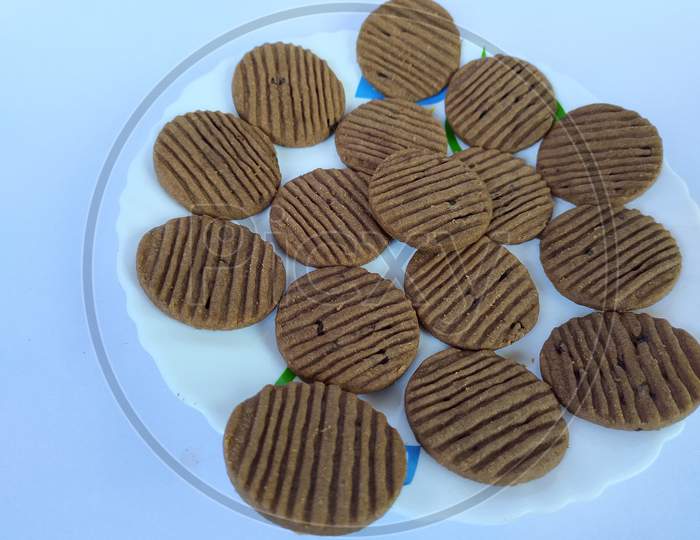 Crispy round biscuits on plate, white background.