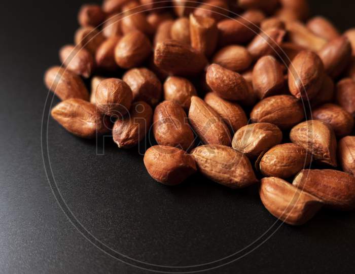A Close Up View Of Brown Color Groundnuts Or Peanuts Groups On Black Background