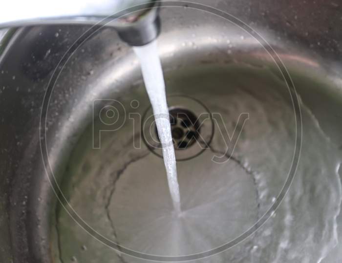 Running water out of a water tap in a metallic kitchen sink
