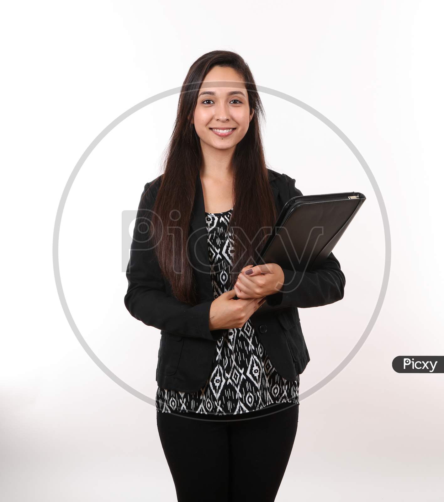 A Young Woman In A Black Suit Holds Her Portfolio As She Smiles.