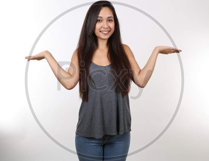 An Attractive Young Female Wearing Jeans And A Grey Tank Top Holds Her Hands Out To Her Sides.