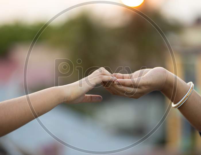 Woman And Child Holding Hands Outdoors At Sunset