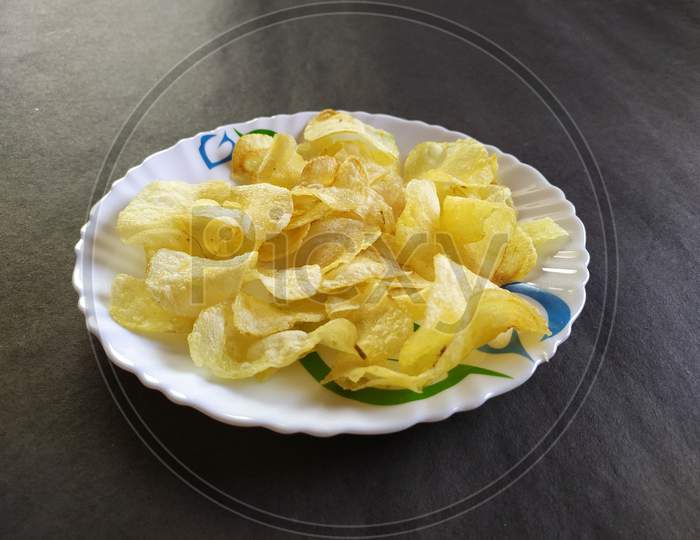 Potato chips on plate, Black background.