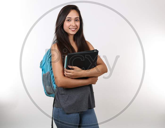 A Smiling Female Student Is Ready For Class With Her Books In Hand.