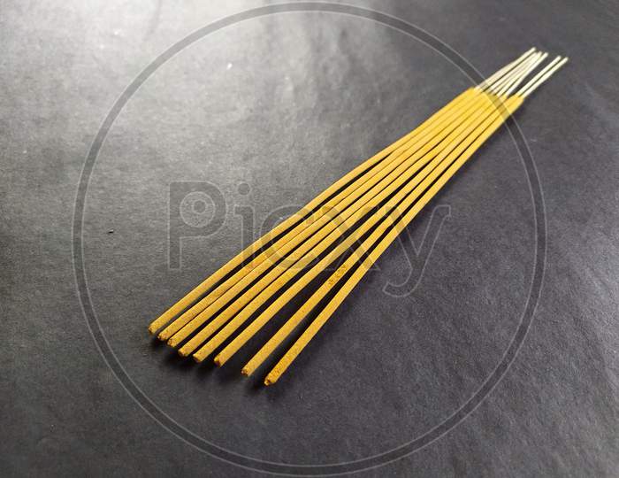 Closeup of incense sticks on black background.