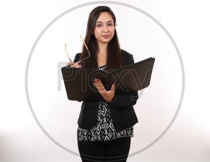 A Young Female In A Black Suit Holds Her Glasses And Portfolio.