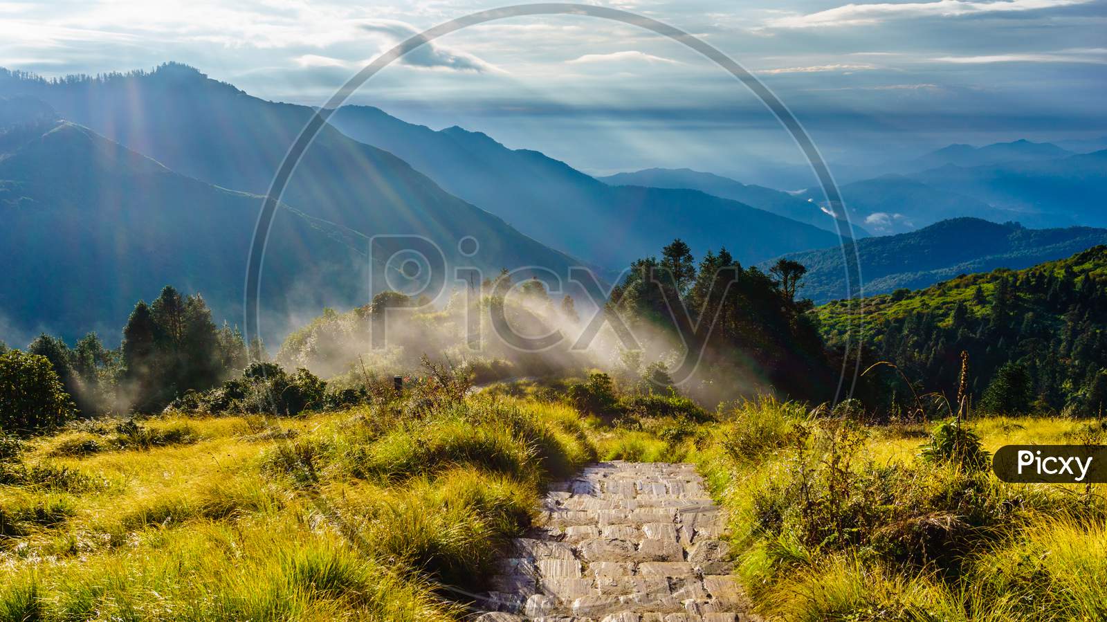 Stone paved trekking trail and filtering lights in the mountains