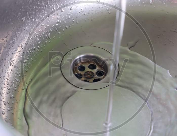 Running water out of a water tap in a metallic kitchen sink