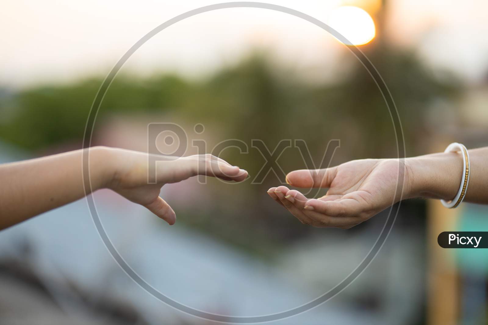 Woman And Child Reaching Out To Hold Hands Outdoors At Sunset