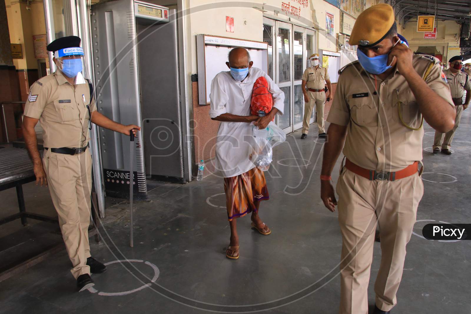 Security personnel direct migrants near a special train which will be on-boarded by migrants to Bihar State from Ajmer railway station during a government-imposed nationwide lockdown as a preventive measure against the COVID-19 or coronavirus, in Ajmer on May 10, 2020.
