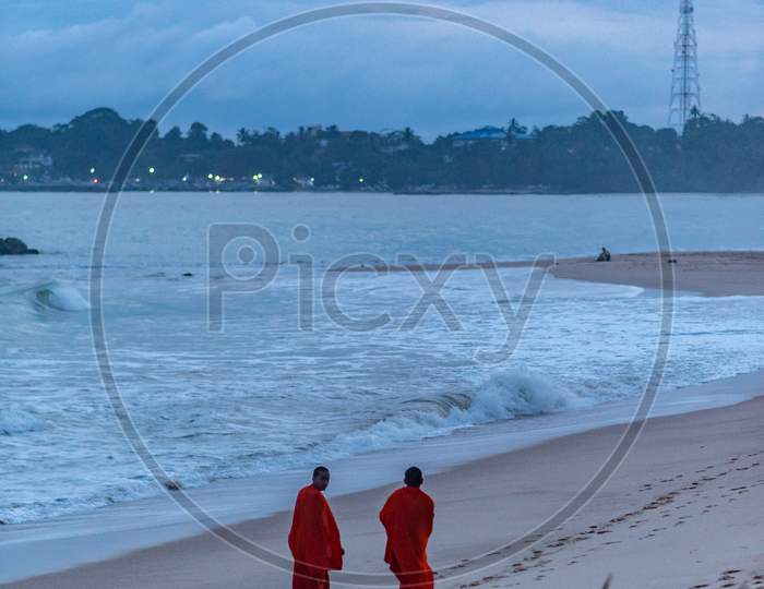 Monks walk the beach in Sunset in the beach of Tangalle, Sri Lanka