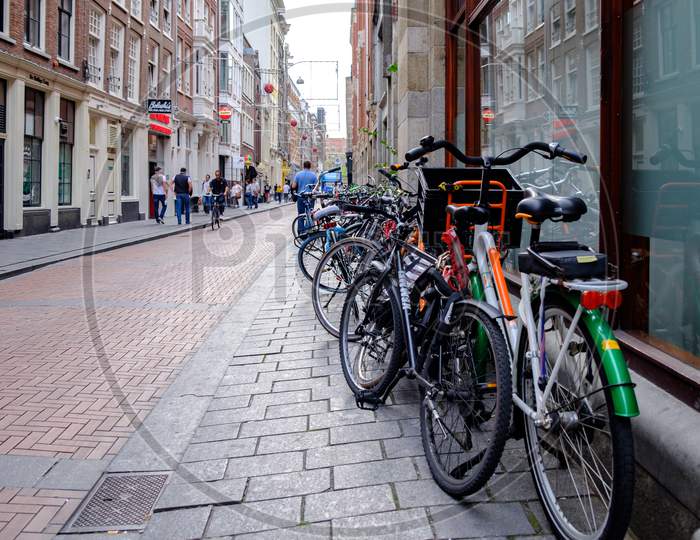 Bicycles Parked In The Street In Amsterdam, Capital Of Netherlands