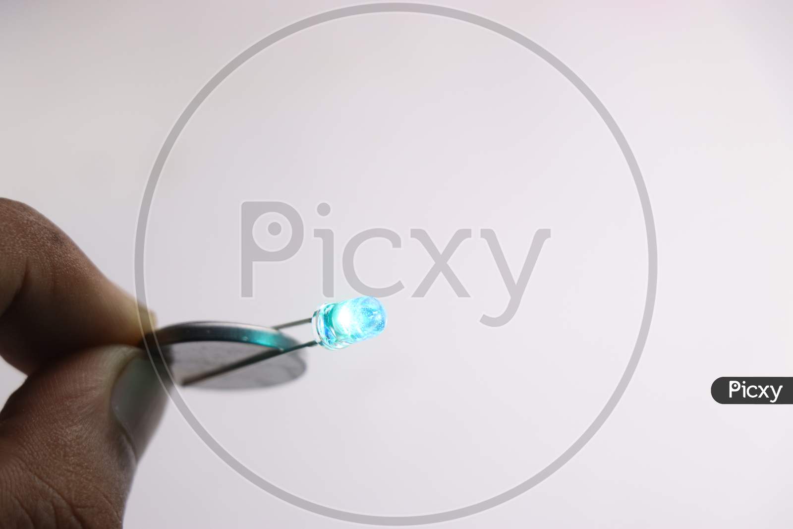 Coin Battery Is Used To Glow The Blue Led On White Background