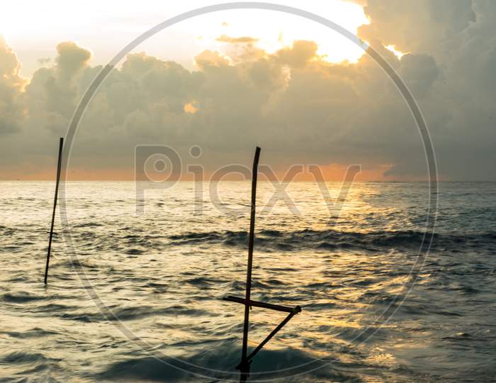 Stormy Sunset In Koggala, Sri Lanka, In The Water The Sticks Where Fishermen Perch.