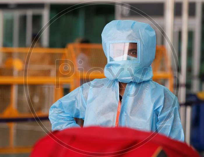 An airport worker in PPE waits to assist passengers board a bus to be taken to a quarantine centre in the city at the Kempegowda International Airport in Bangalore, India, May 11, 2020. Three hundred twenty six passengers stranded in the UK due to the covid-19 lockdown arrived in an Air India flight