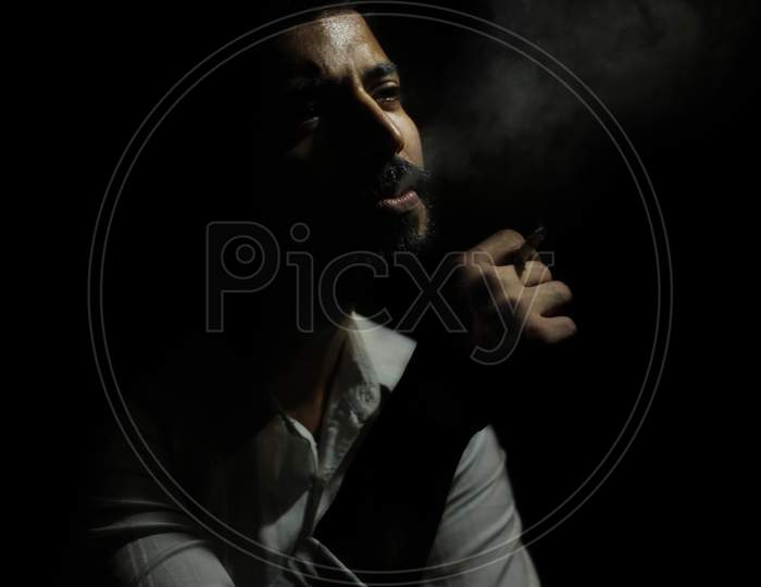 May 2020, A handsome guy smoking cigarette in a dark room.
