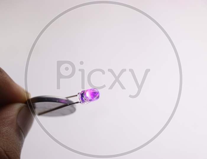 Led Bulb Connected To Coin Battery Which Is Glowing Purple In Color