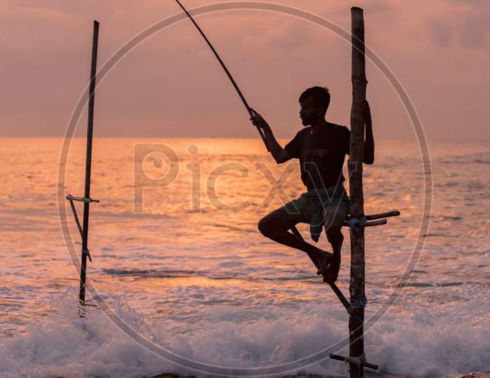 Silhouettes Of The Traditional Sri Lankan Stilt Fishermen On A Stormy In Koggala, Sri Lanka. Stilt Fishing Is A Method Of Fishing Unique To The Island Country Of Sri Lanka