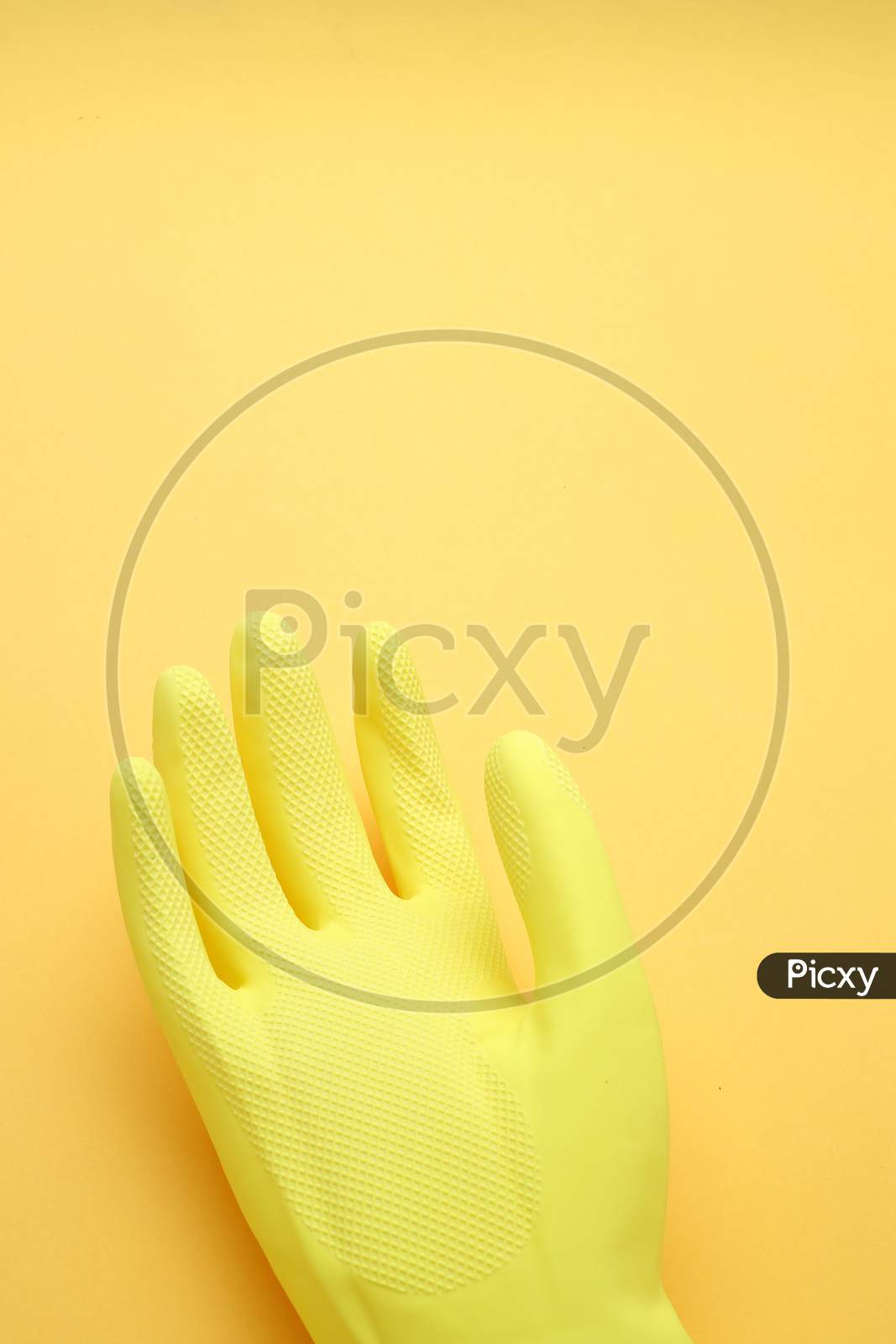 Hand In Yellow Glove Isolated On Yellow Background,Top View