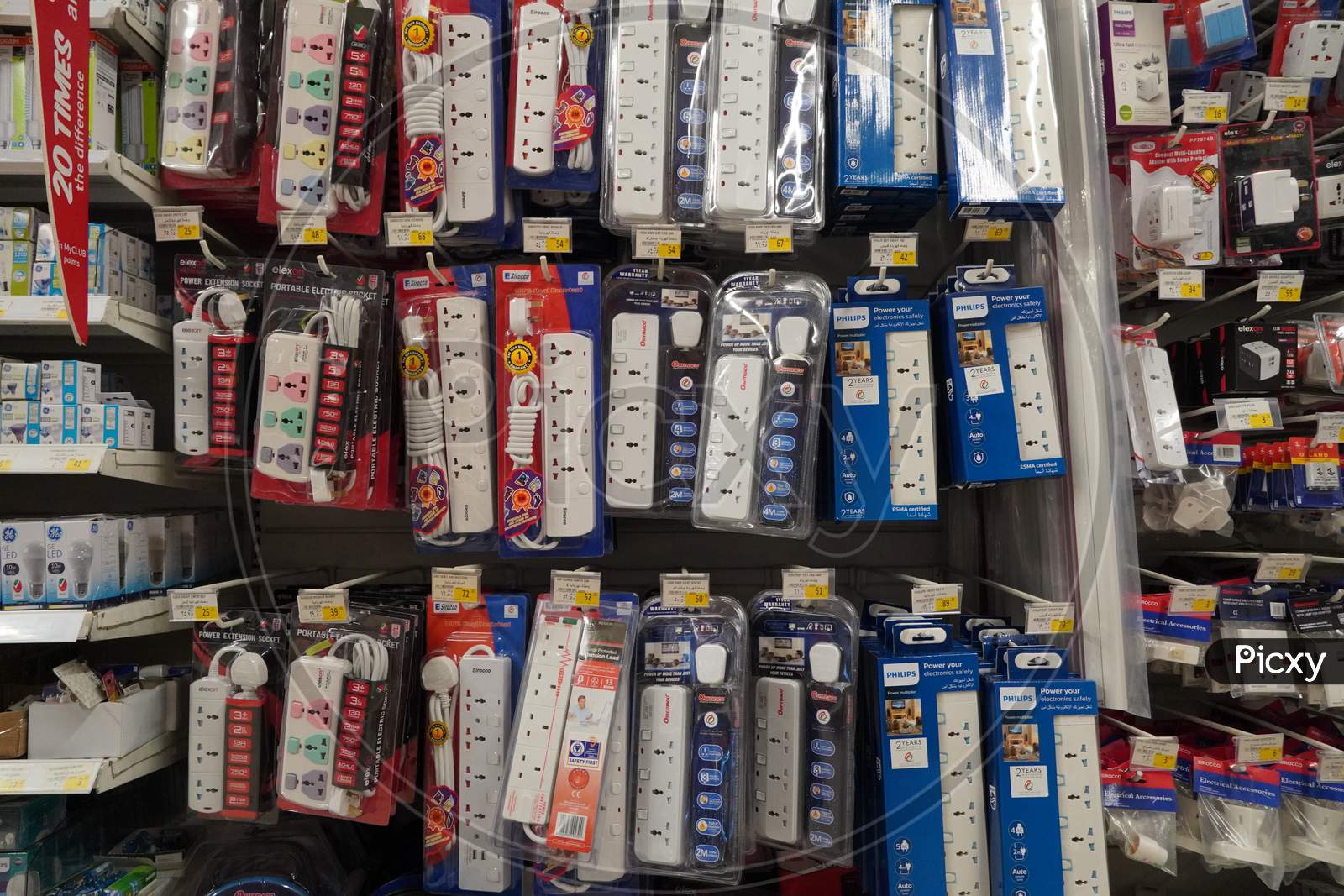 Selection Of Extension 3 Pin Plug Socket Wire On Supermarket. Many Adapter Power Plug Or Extension Cord Hang On The Shelf. Packed Ready Different Kinds Of Power Strips.