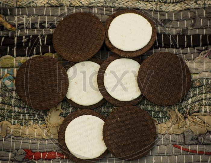 Chocolate Cookies (Biscuit) With Vanilla Cream Made Of Milk With Textured Cloth In Background.