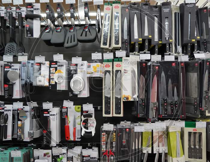 Kitchen Tools Hanging In Shop. Large Set And Variety Of Different Manufacturers On Shelves In Store. Kitchenware, Knives, Spatulas, Ladle, Tongs, Spoons, Silicon Tools.