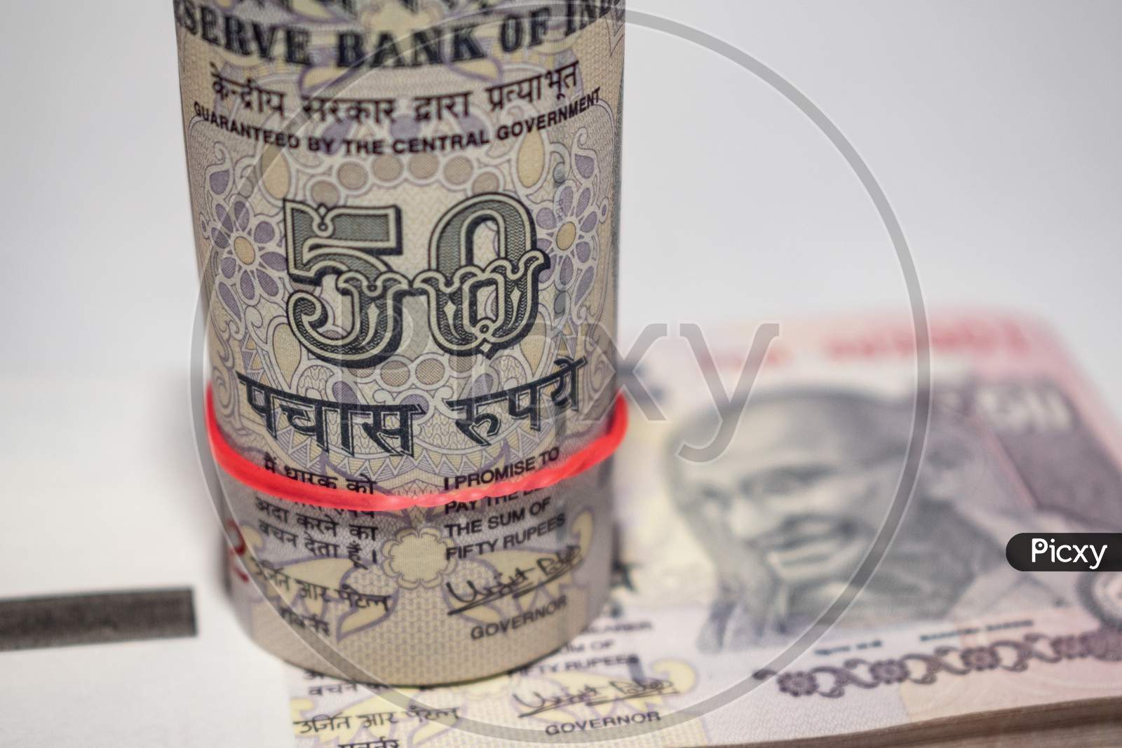 Roll of Indian currency notes of 50 rupees put on the bundle of notes