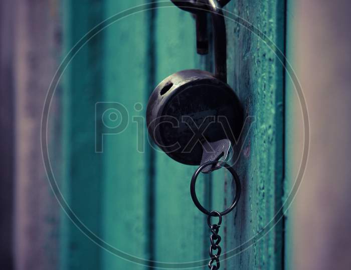 An Opened Lock And Key Hanging In The Wooden Door