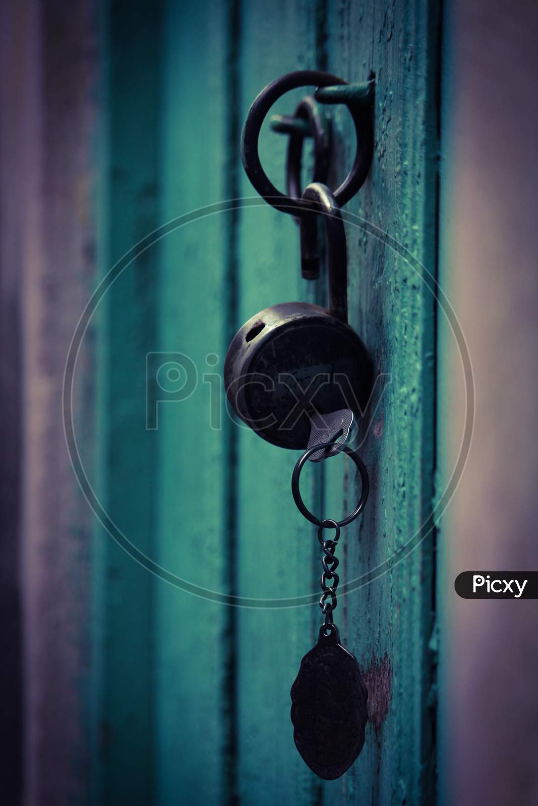 An Opened Lock And Key Hanging In The Wooden Door