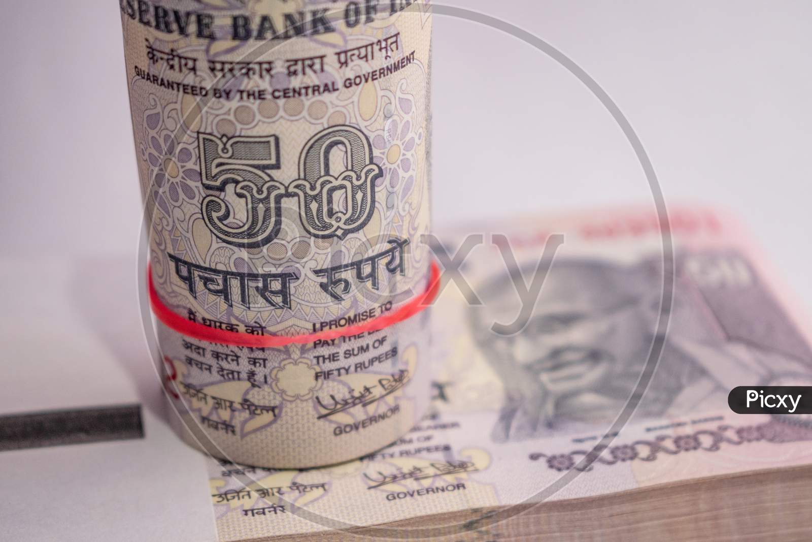 Roll of Indian currency notes of 50 rupees put on the bundle of notes