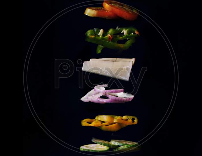 A vegetable sandwich is placed between two hands with a black background.