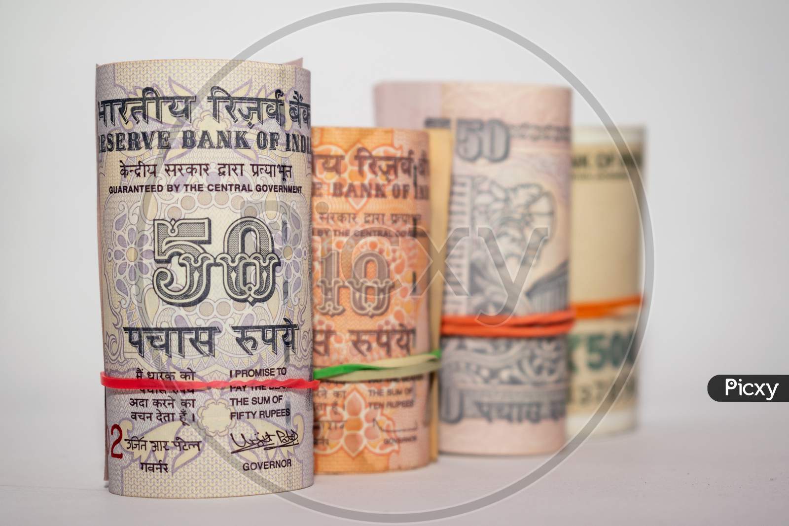 Rolls and bundles of Indian currency notes placed on a white background