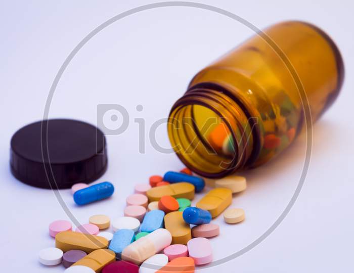 Brown Glass Bottle With Pills Of Various Colors. Drugs For Use In Humans. Pills On White Background.