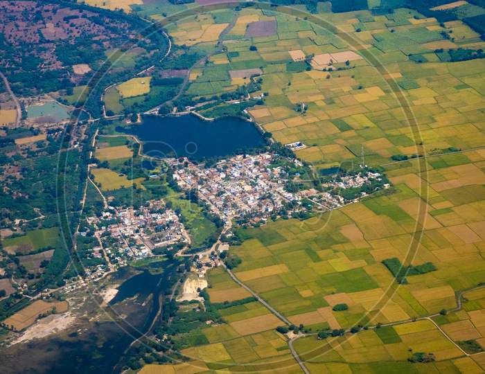 Aerial View Of a Town Or Village Surrounded With Green Fields And Roads From Flight Window