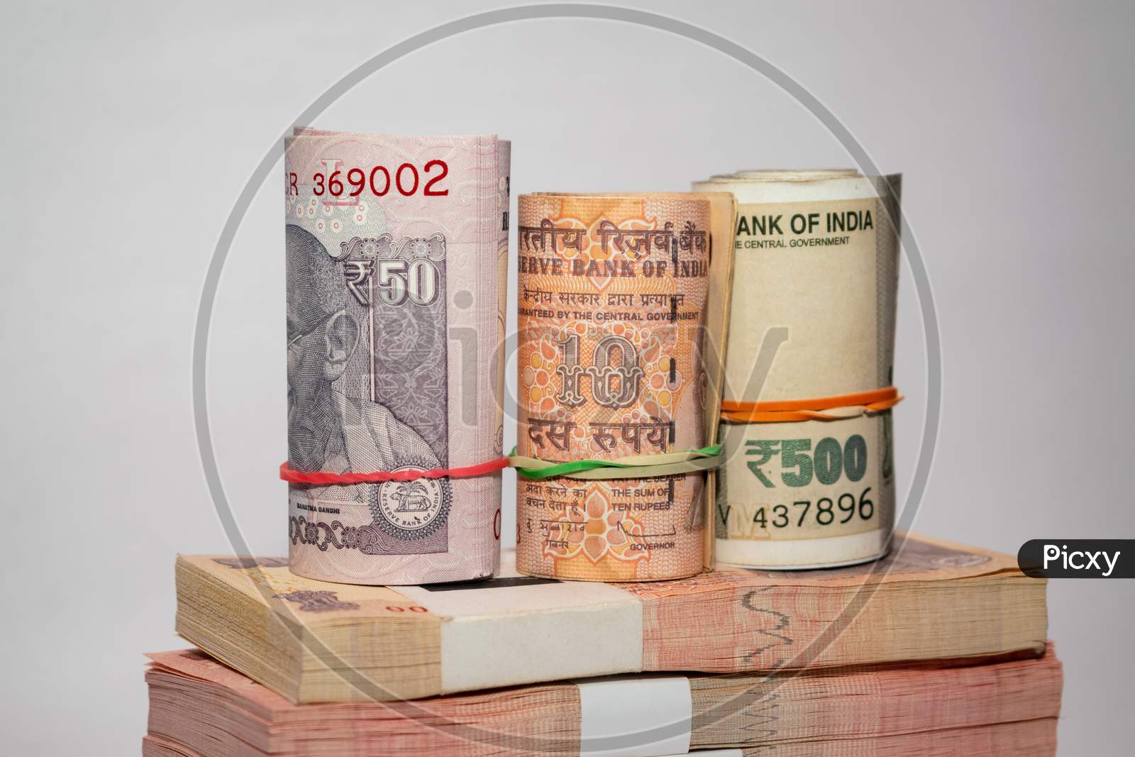Rolls and bundles of Indian currency notes placed on a white background
