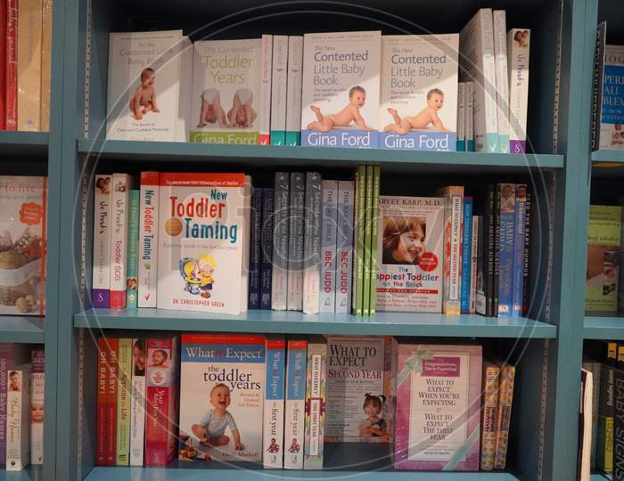 Bookshelf In Library With Many Parenting Books For Sale. Parenting, Toddler Guidebooks. Children Books. Toddler Books. What To Expect When You Are Expecting. Pregnancy Guide -
