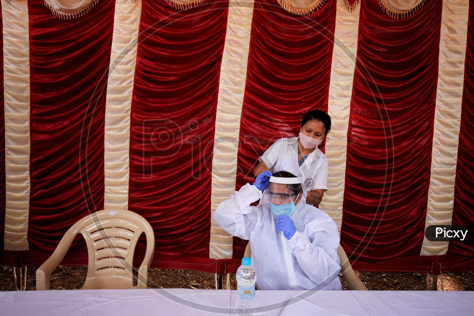 A nurse assists a doctor wear her face shield as they prepare to test police personnel for covid-19 during a health screening camp for the police forces in Bangalore, India.
