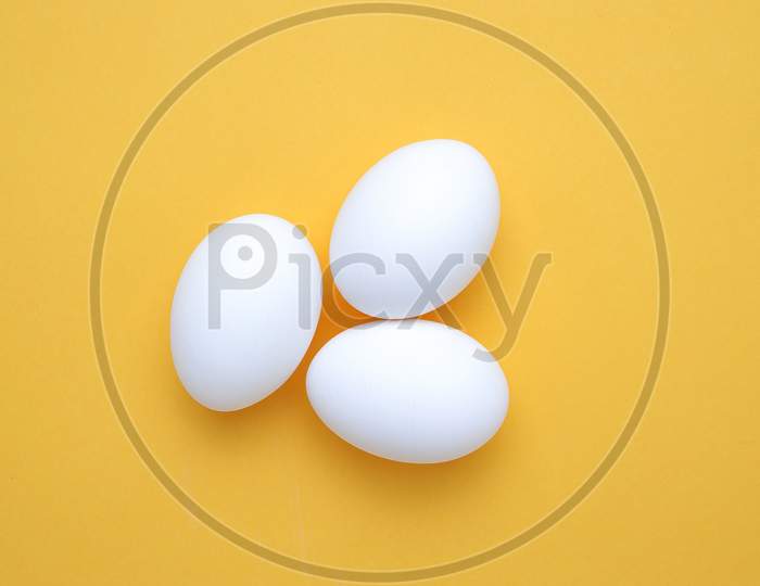 Eggs,Three White Eggs On The Yellow Background In Center,Copy Space For The Ads