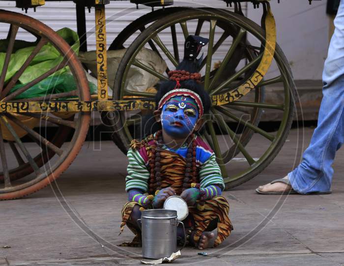 A young child dressed as the Hindu deity Shiva waiting for alms from pilgrims in Pushkar, Rajasthan, India.