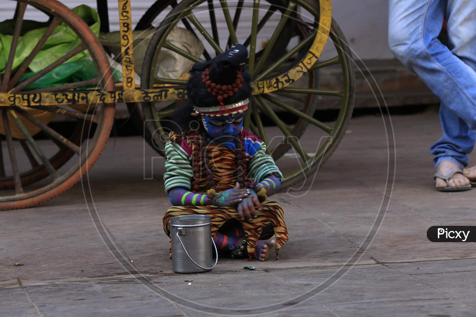 A young child dressed as the Hindu deity Shiva waiting for alms from pilgrims in Pushkar, Rajasthan, India.