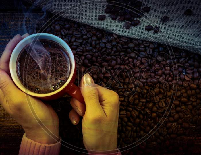 cup of coffee and coffee beans in a sack on dark background