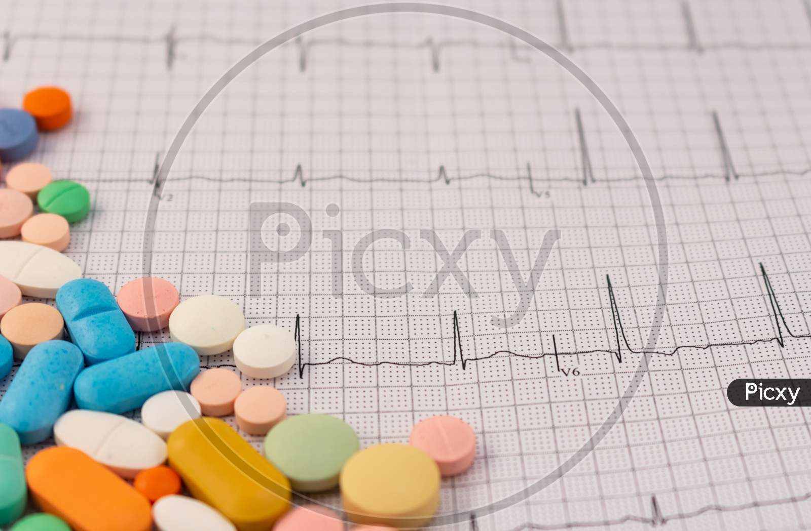 Pills Of Different Sizes And Colors On An Electrocardiogram Sheet.
