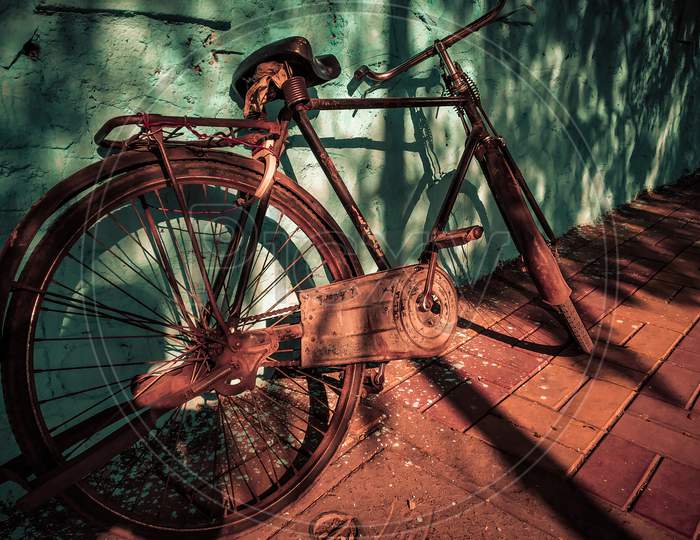 Old Vintage Rustic Metallic Bicycle With Blue Wall As A Background With Light And Shadow Can Be Used As A Advertising.